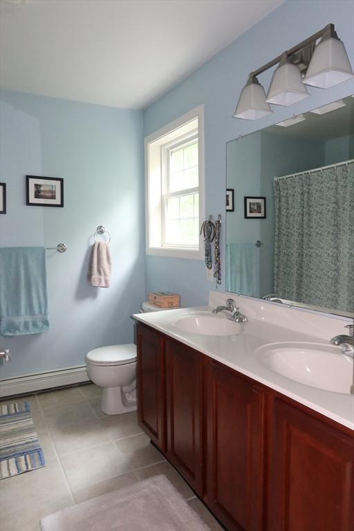 12 Sterling Ln Unit 12, Walpole, MA 02081 - full bath with a baseboard heating unit, double vanity, toilet, and tile patterned floors