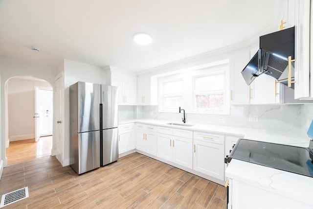 kitchen featuring arched walkways, freestanding refrigerator, light countertops, a sink, and visible vents