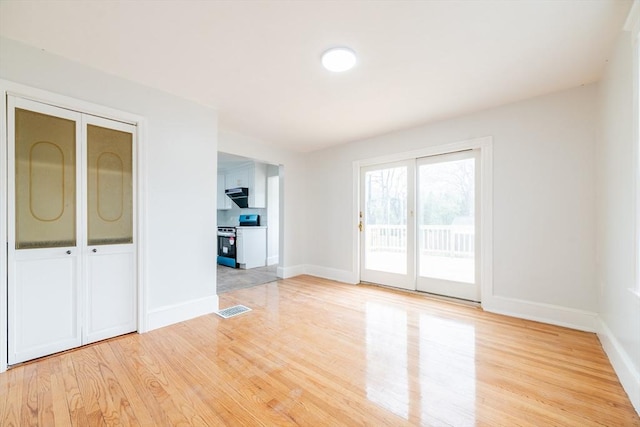 unfurnished room with visible vents, light wood-style flooring, and baseboards