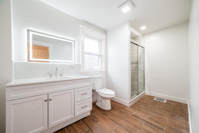 full bathroom featuring wood finished floors, toilet, vanity, visible vents, and a stall shower