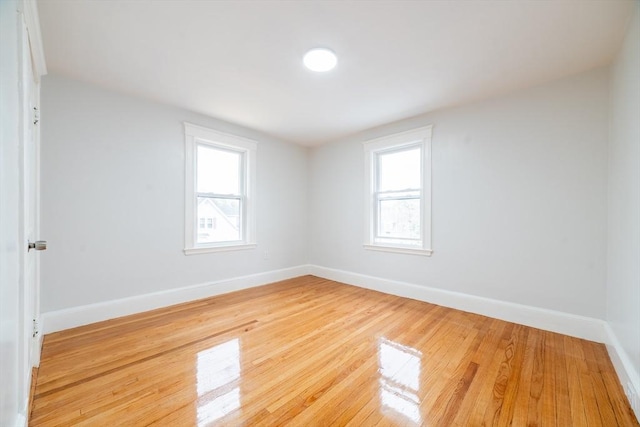 unfurnished room featuring a healthy amount of sunlight, light wood finished floors, and baseboards