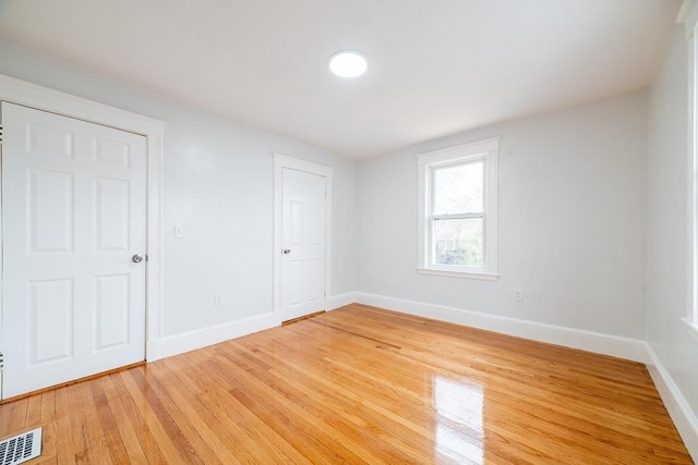 unfurnished bedroom featuring visible vents, light wood-style floors, and baseboards