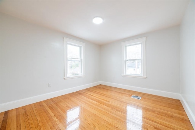 unfurnished room with baseboards, visible vents, and light wood finished floors