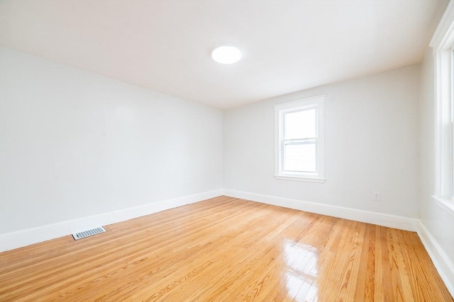 unfurnished room featuring baseboards, visible vents, and light wood finished floors