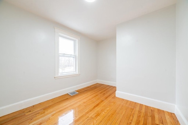 unfurnished room featuring baseboards, visible vents, and wood finished floors