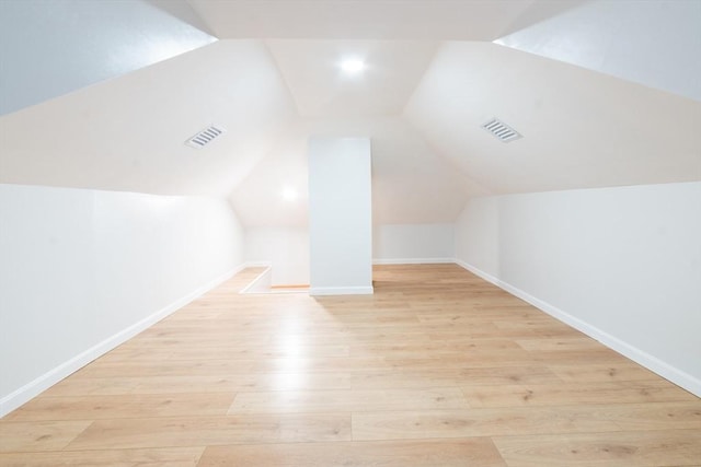 additional living space with visible vents, baseboards, vaulted ceiling, and light wood-style floors