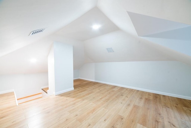 bonus room featuring lofted ceiling, wood finished floors, visible vents, and baseboards