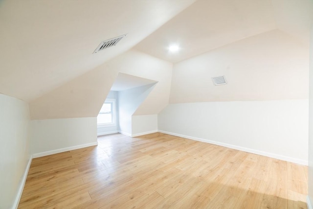 additional living space featuring lofted ceiling, wood finished floors, visible vents, and baseboards