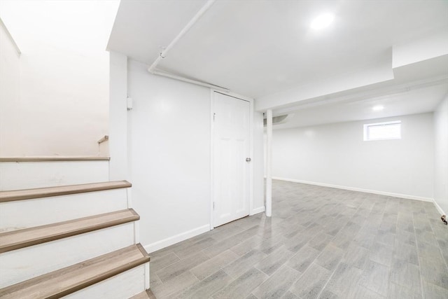 below grade area with stairway, wood finished floors, recessed lighting, and baseboards