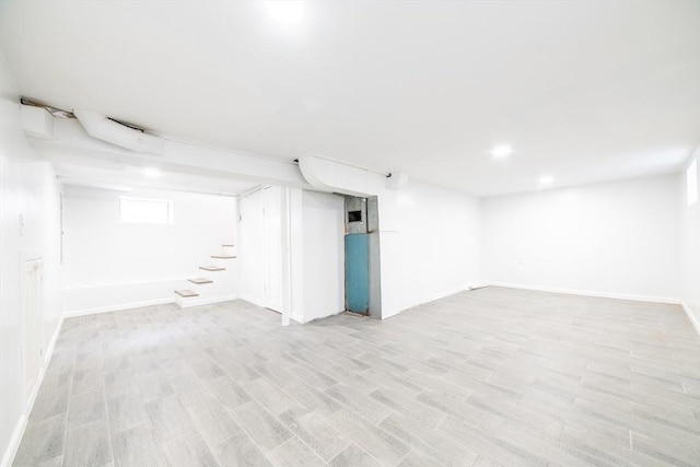 basement with stairway, light wood-type flooring, and baseboards