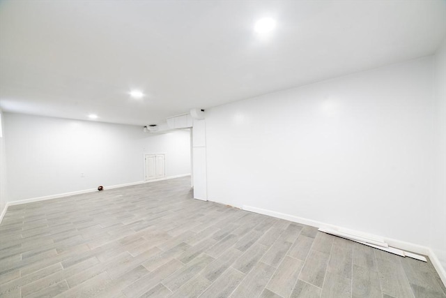 finished below grade area with baseboards, recessed lighting, and light wood-style flooring