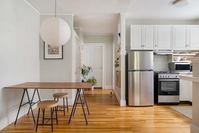 9 Ellery St Unit 33, Cambridge, MA 02138 - kitchen featuring appliances with stainless steel finishes, under cabinet range hood, white cabinets, light wood-style flooring, and crown molding