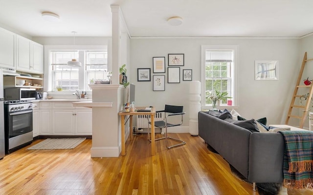 9 Ellery St Unit 33, Cambridge, MA 02138 - kitchen featuring wall oven, light wood finished floors, white cabinetry, ornamental molding, and light countertops