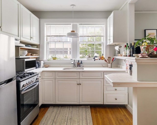 9 Ellery St Unit 33, Cambridge, MA 02138 - kitchen featuring appliances with stainless steel finishes, a sink, white cabinets, and light wood-style flooring