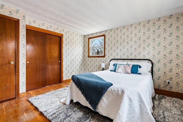 bedroom with wallpapered walls, baseboards, and wood finished floors