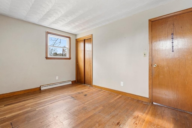 unfurnished bedroom with hardwood / wood-style flooring, baseboards, a closet, and a baseboard radiator