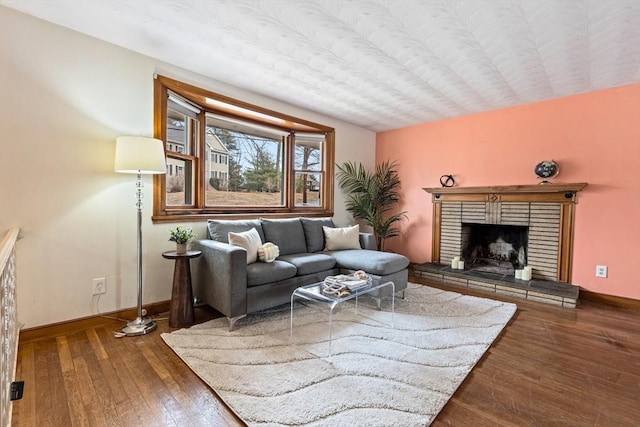 living room with dark wood-style floors, a brick fireplace, and baseboards