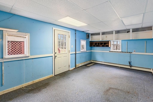 carpeted empty room featuring a paneled ceiling and baseboards