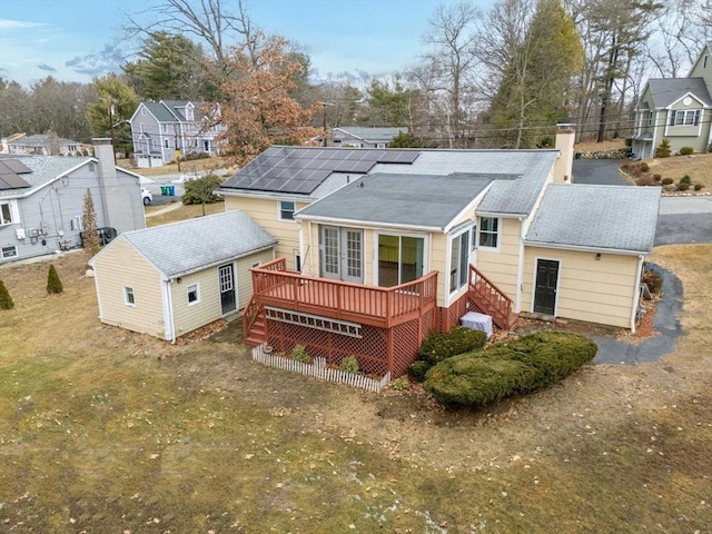 back of house with a deck, a residential view, solar panels, and a chimney