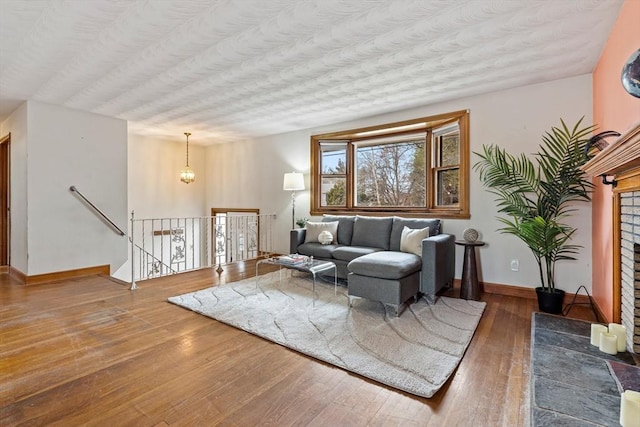 living area featuring baseboards, wood-type flooring, and a textured ceiling