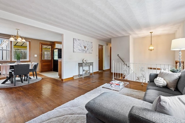 living area featuring baseboards, a notable chandelier, and hardwood / wood-style floors