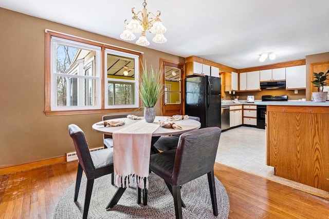 dining room with light wood-style flooring, an inviting chandelier, and baseboards