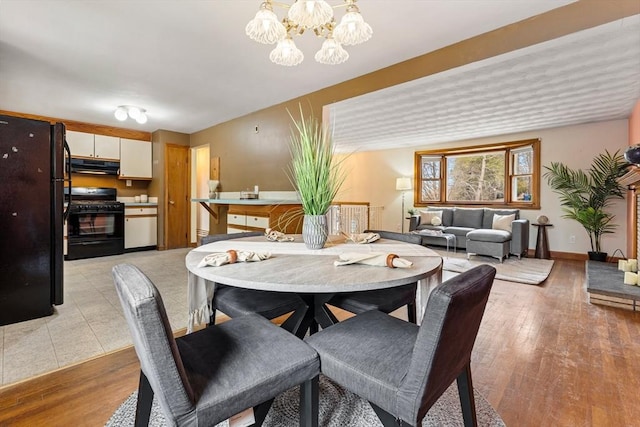 dining space featuring baseboards, a notable chandelier, and light wood finished floors