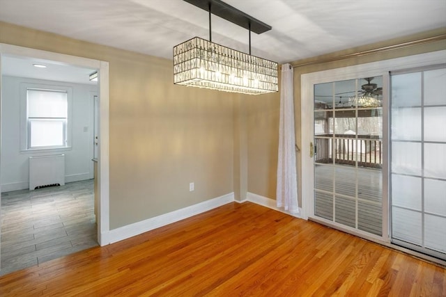 unfurnished dining area with ceiling fan, radiator, and light hardwood / wood-style floors