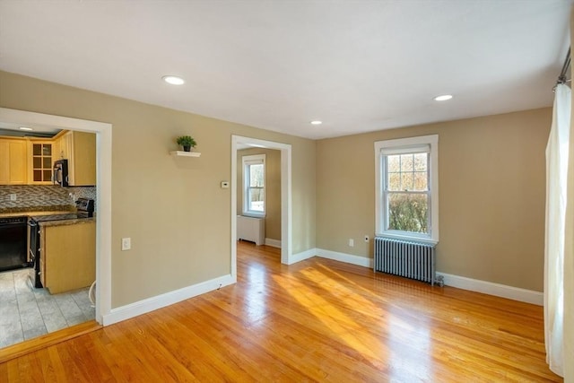 unfurnished living room featuring radiator heating unit and light hardwood / wood-style floors