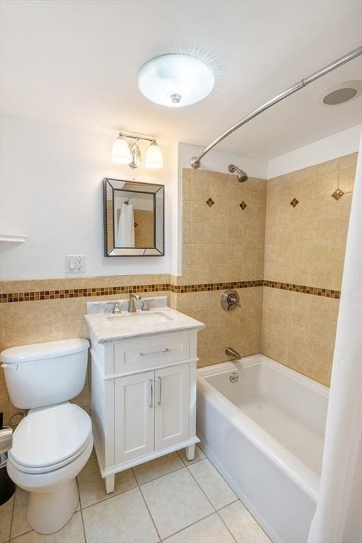 full bathroom featuring tile walls, tiled shower / bath combo, vanity, tile patterned floors, and toilet