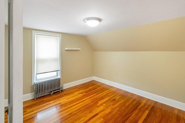 bonus room featuring wood-type flooring, vaulted ceiling, and radiator