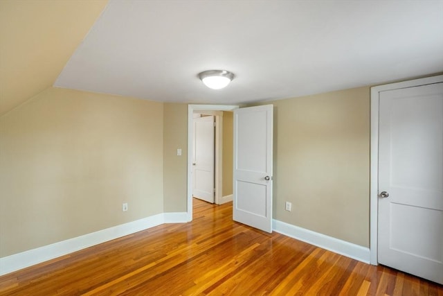 unfurnished bedroom featuring hardwood / wood-style floors and vaulted ceiling