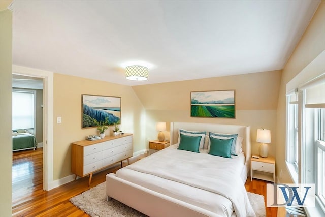 bedroom with lofted ceiling and light wood-type flooring