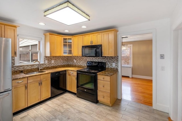 kitchen featuring light hardwood / wood-style floors, sink, black appliances, and dark stone counters