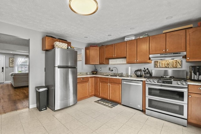 11 Fernwood Dr Unit D, Leominster, MA 01453 - kitchen featuring appliances with stainless steel finishes, under cabinet range hood, a sink, brown cabinets, and light countertops