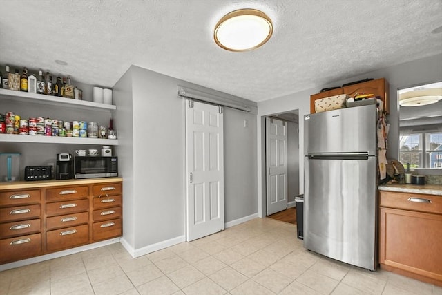 11 Fernwood Dr Unit D, Leominster, MA 01453 - kitchen with appliances with stainless steel finishes, brown cabinetry, light countertops, a textured ceiling, and light tile patterned flooring