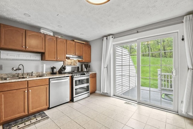 11 Fernwood Dr Unit D, Leominster, MA 01453 - kitchen with stainless steel appliances, a sink, under cabinet range hood, light countertops, and brown cabinets