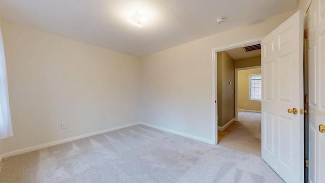 spare room with baseboards, visible vents, and light colored carpet