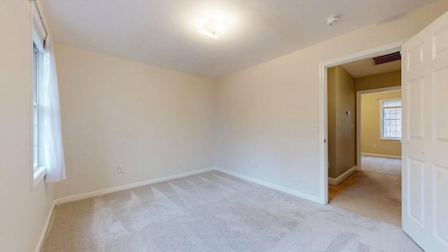 spare room featuring baseboards, visible vents, and light colored carpet