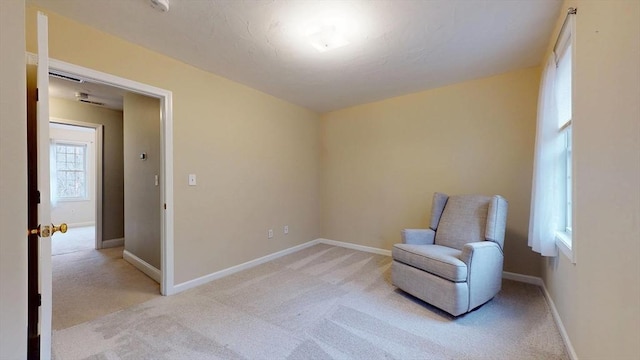 living area featuring baseboards and light colored carpet