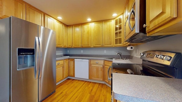 kitchen featuring a sink, glass insert cabinets, light wood-type flooring, stainless steel appliances, and recessed lighting