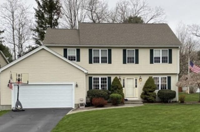 colonial house with aphalt driveway, a garage, and a front lawn