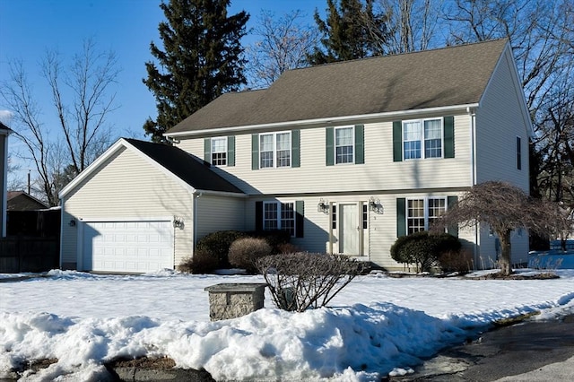 colonial home with roof with shingles and an attached garage