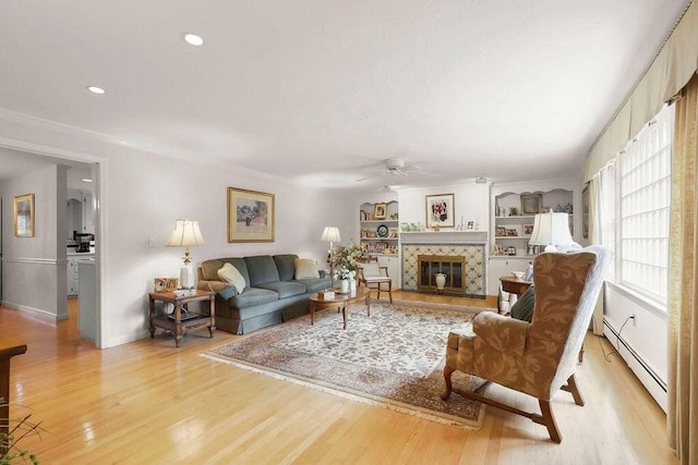 8 Viking Rock Rd, Yarmouth, MA 02664 - living room with a baseboard heating unit, ceiling fan, light wood-style flooring, a tiled fireplace, and recessed lighting