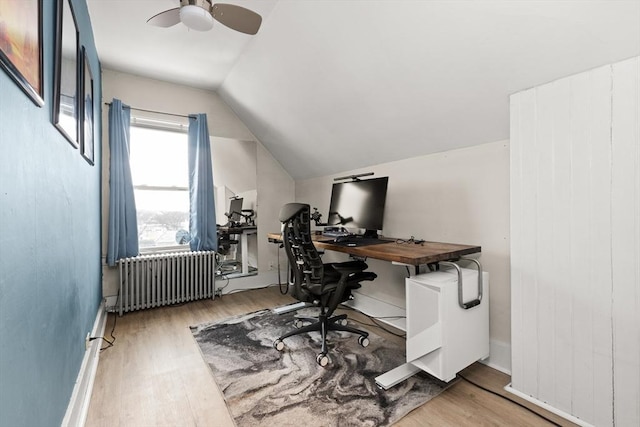 office space featuring ceiling fan, radiator, wood finished floors, and vaulted ceiling