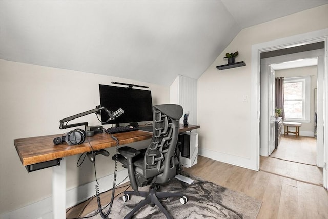 home office featuring baseboards, wood finished floors, and vaulted ceiling