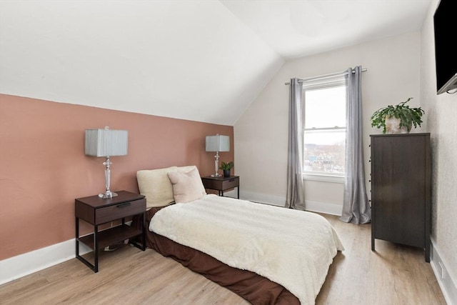 bedroom with lofted ceiling, light wood-style floors, and baseboards