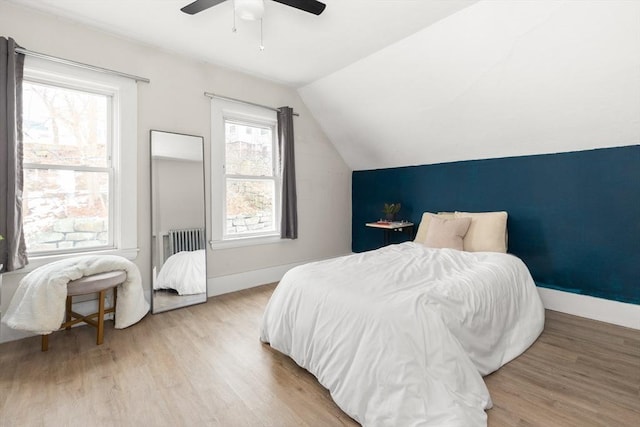 bedroom featuring baseboards, light wood-style flooring, a ceiling fan, and vaulted ceiling