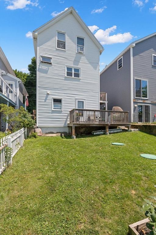 back of house with a lawn, a deck, and fence