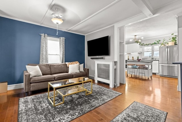 living room featuring plenty of natural light, light wood-style flooring, and ornamental molding